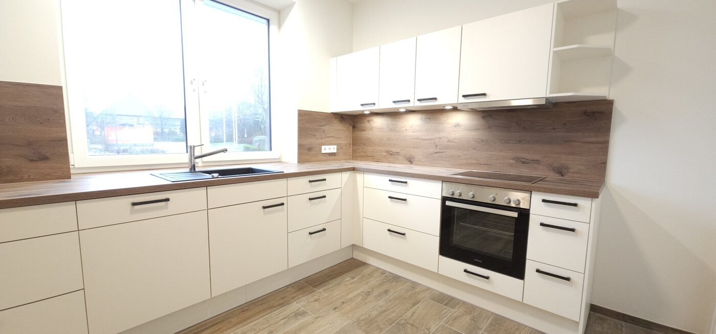 L-förmige Küche in einem hellen Farbton mit dunkler Holzarbeitsplatte.