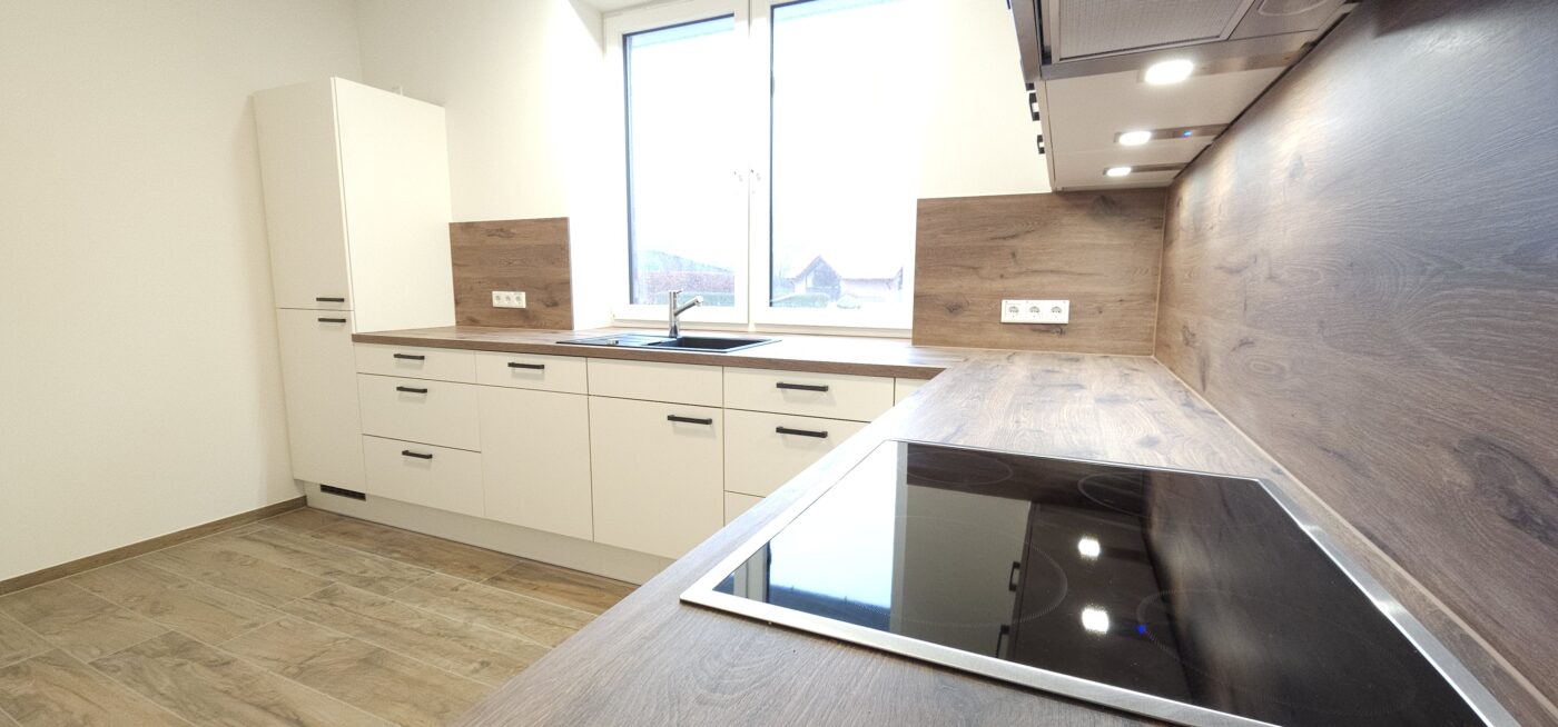 L-förmige Küche in einem hellen Farbton mit dunkler Holzarbeitsplatte.