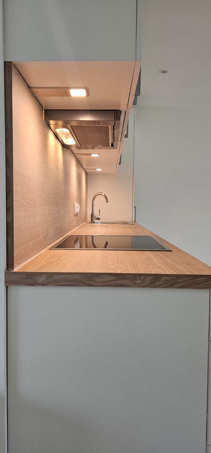 Seitenansicht auf eine Küchenzeile in weiß mit Holz